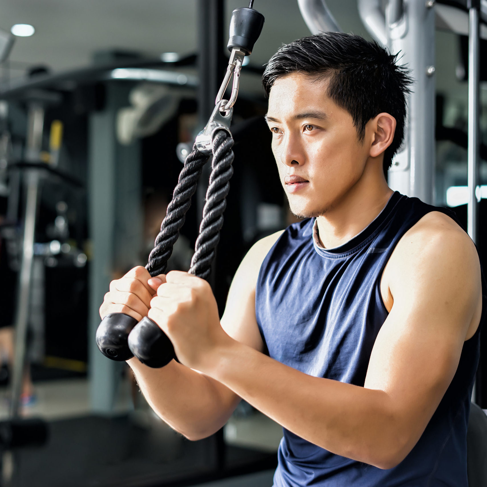 Strong handsome asian man exercising at the gym